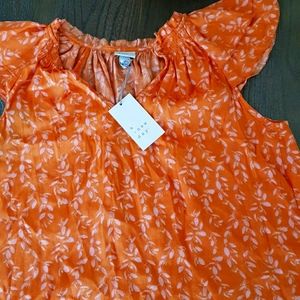 A orange shirt with flowers designed.